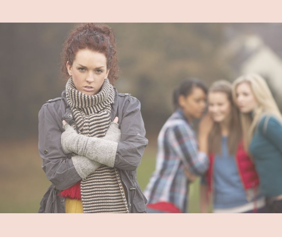 Slika prikazuje djevojku iza koje stoji grupa djevojaka koje razgovaraju. Doima se kao da pričaju o njoj, da je ogovaraju.